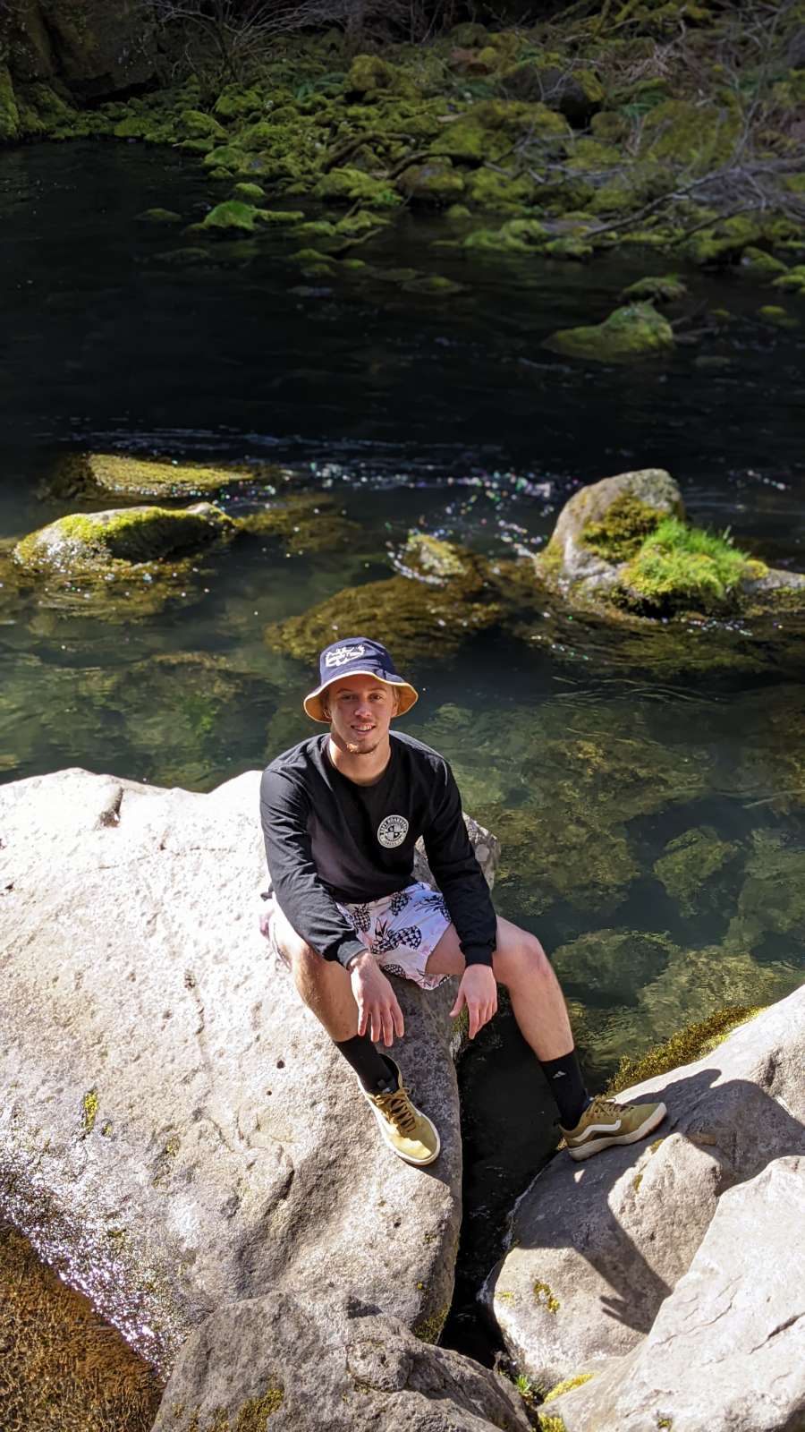 Joshua Bettencourt, OP Trip Coordinator, shown sitting on rocks near water