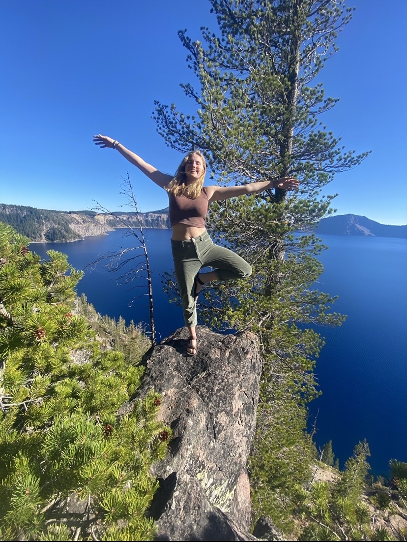 Kate Hicks, OP Trip Coordinator, shown in a yoga pose on a rock overlooking Crater Lake.