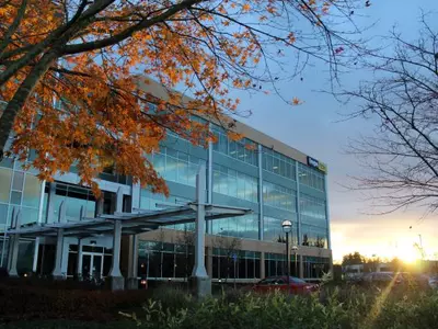 Picture of Oregon Tech's portlad metro campus building at sunset with fall leaves in the foreground