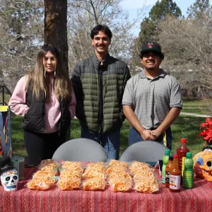 Three students standing behind a table