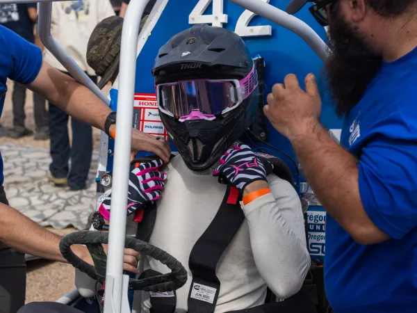 Student with helmet on driving Baja vehicle