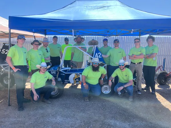 Team of students standing around Baja vehicle