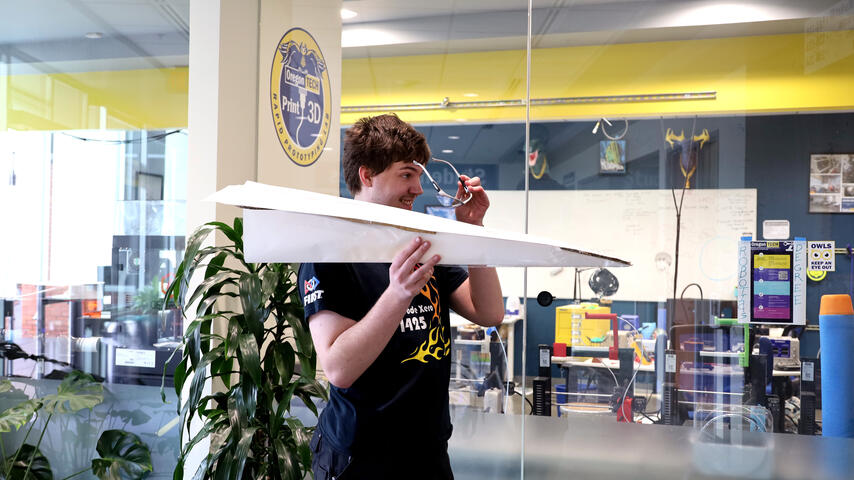 Student launching a giant paper airplane at a student competition event