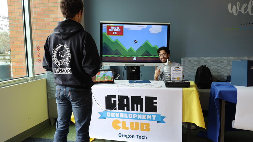 Student talking to Game Development Club member at Portland-Metro club fair